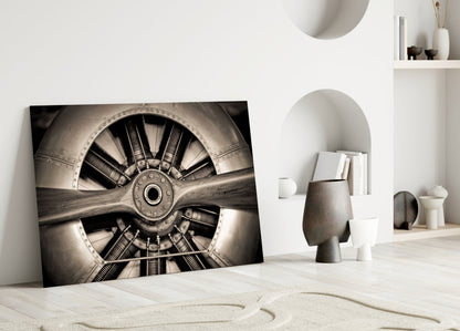 Sepia-toned propeller glass wall art leaning against white wall in minimalist interior with sand and ceramic decor.