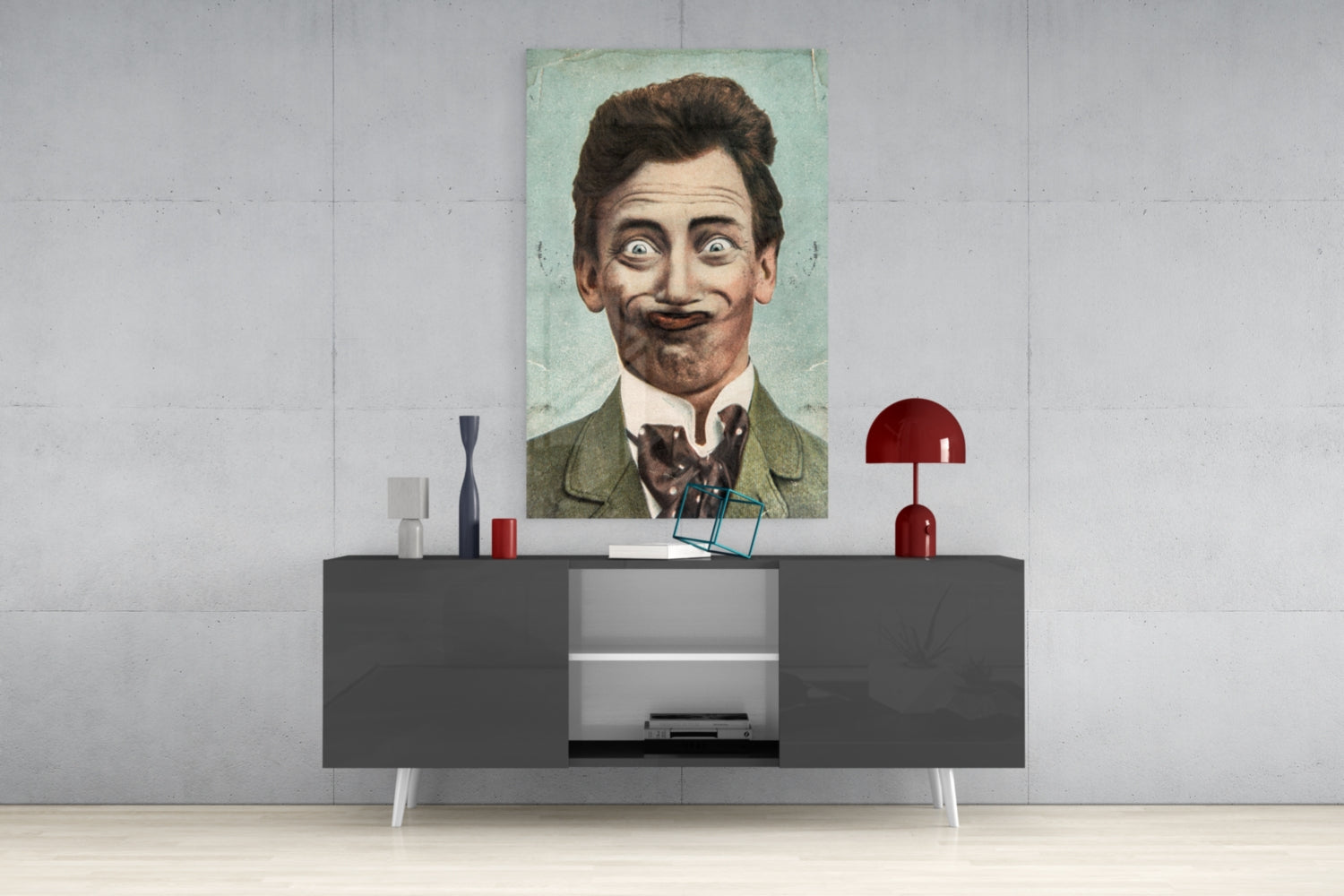 Vintage portrait of a mustachioed gentleman in green jacket displayed on white wall above modern gray console table with red lamp and decorative objects.