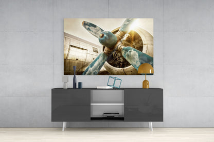 Vintage airplane propeller glass wall art displaying weathered blue and gold tones, mounted above gray media console in modern interior setting.