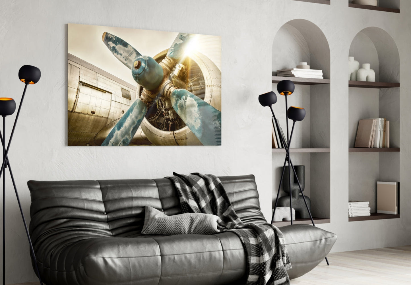 Vintage aircraft propeller and engine close-up in sepia tones displayed above black leather sofa in modern living room.