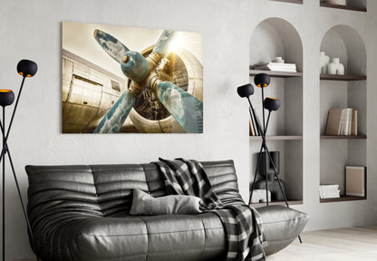 Vintage aircraft propeller and engine close-up in sepia tones displayed above black leather sofa in modern living room.