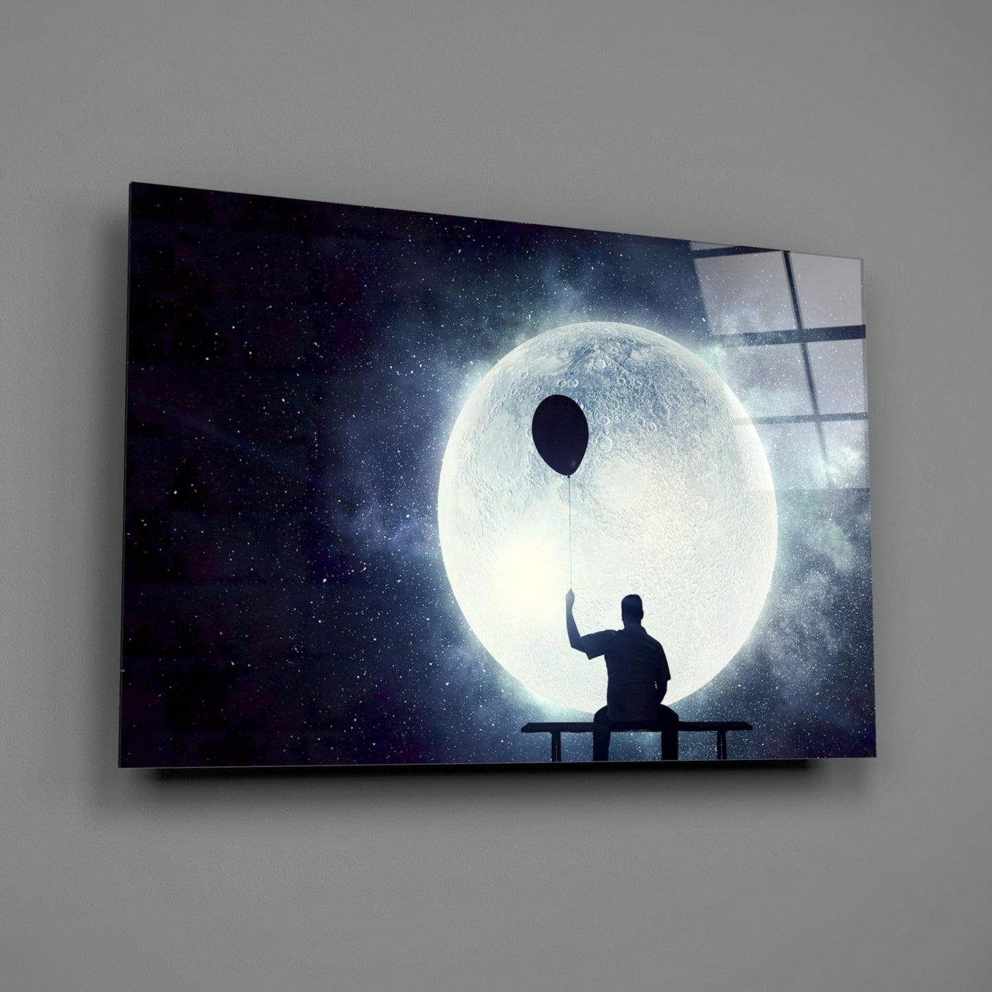Silhouetted figure sitting on bench holding balloon string toward luminous moon against starry night sky on glass panel.