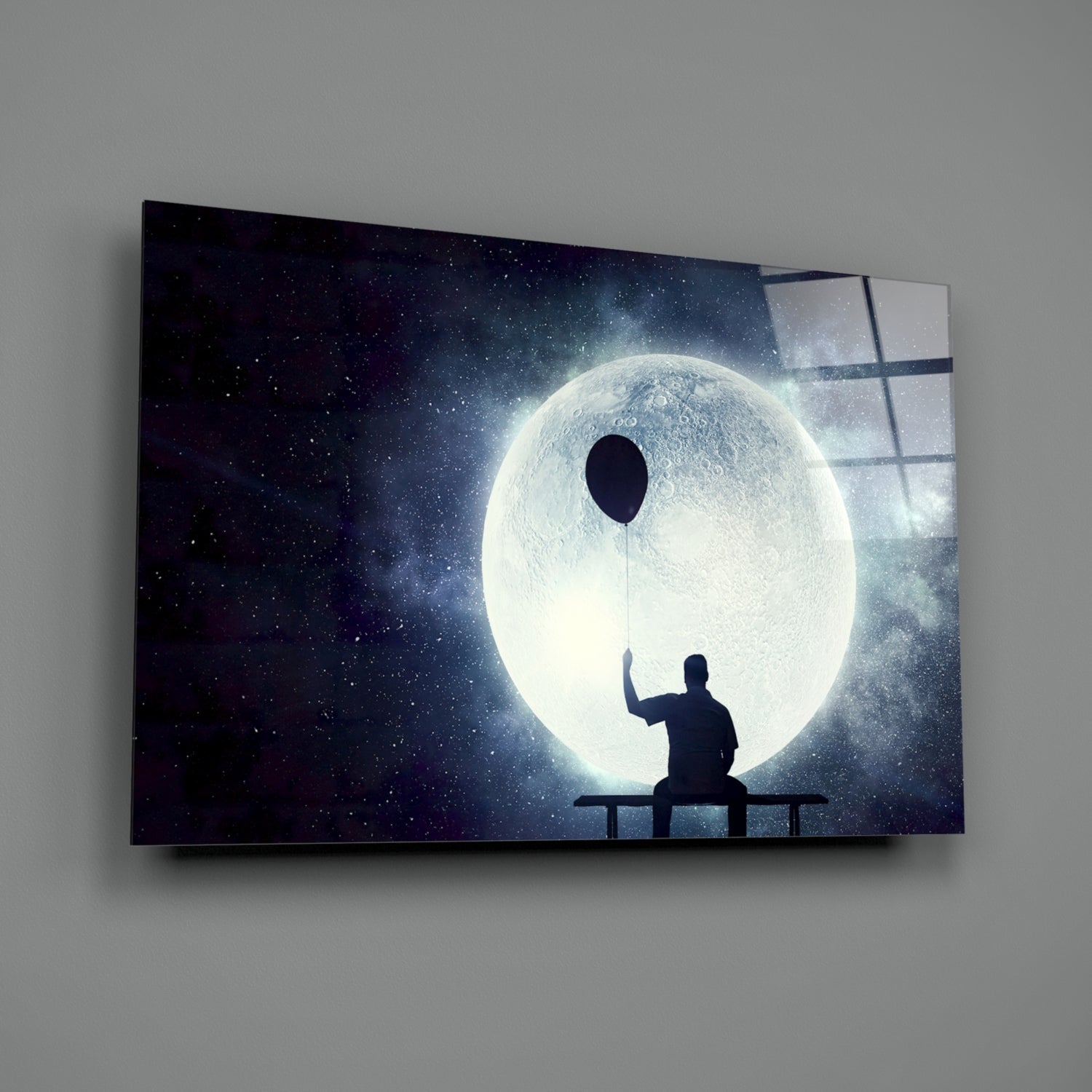 Silhouetted figure sitting on bench holding balloon string toward luminous moon against starry night sky on glass panel.