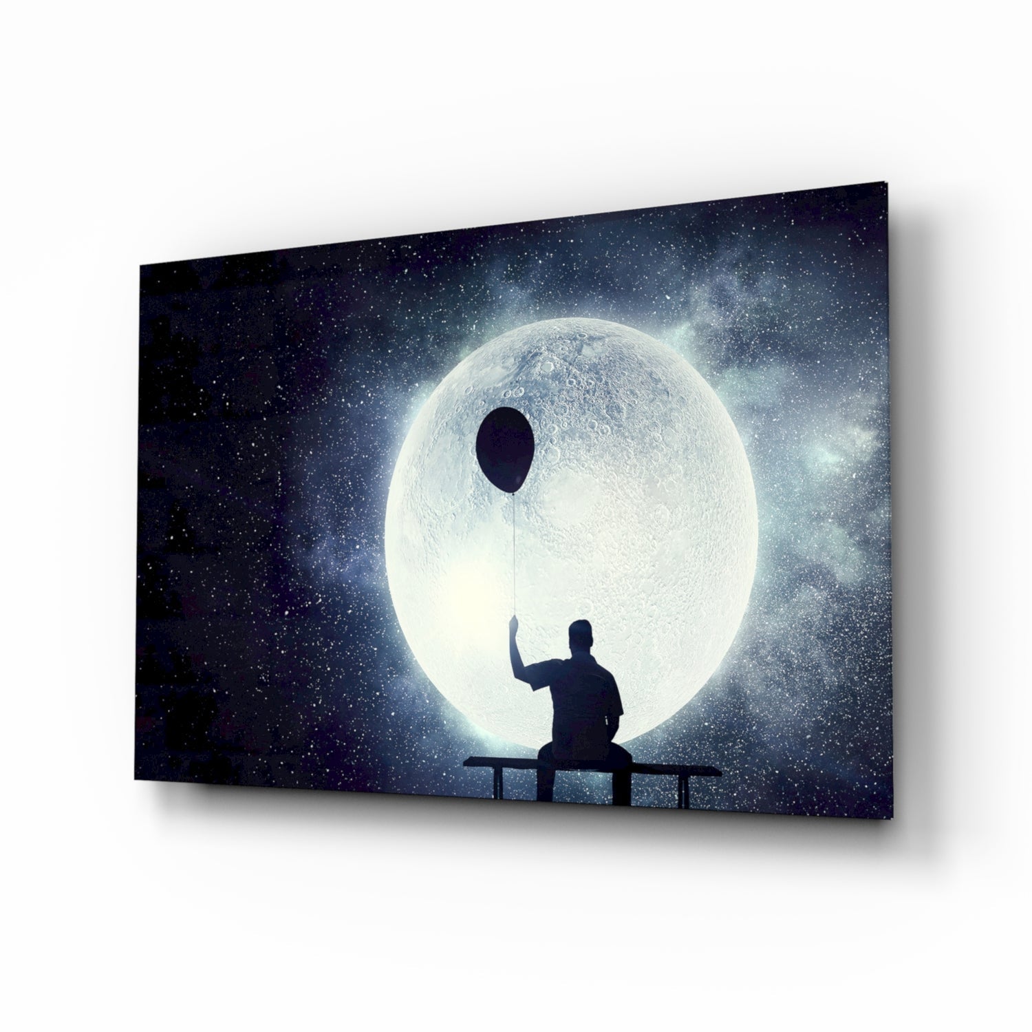 Silhouetted figure on railing holding balloon string toward large glowing moon against starry night sky on glass wall art.