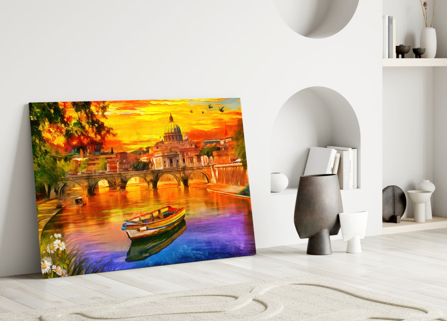 Colorful glass wall art depicting St. Peter's Basilica at sunset with boats and bridge, leaning against white interior wall.