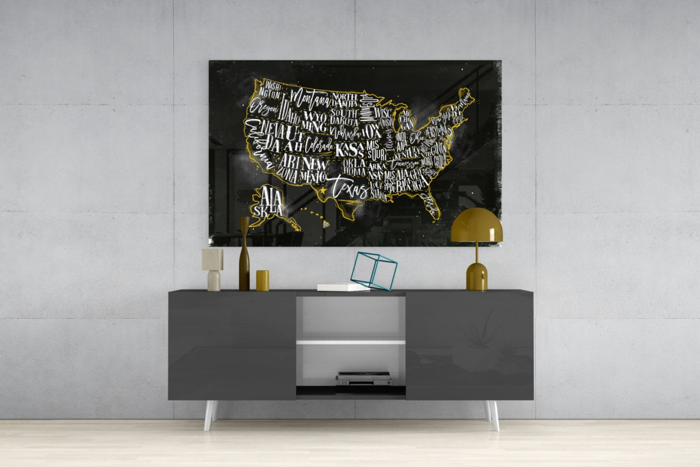 Black glass USA map with gold state outlines and white lettering displayed above gray media console in modern interior setting.