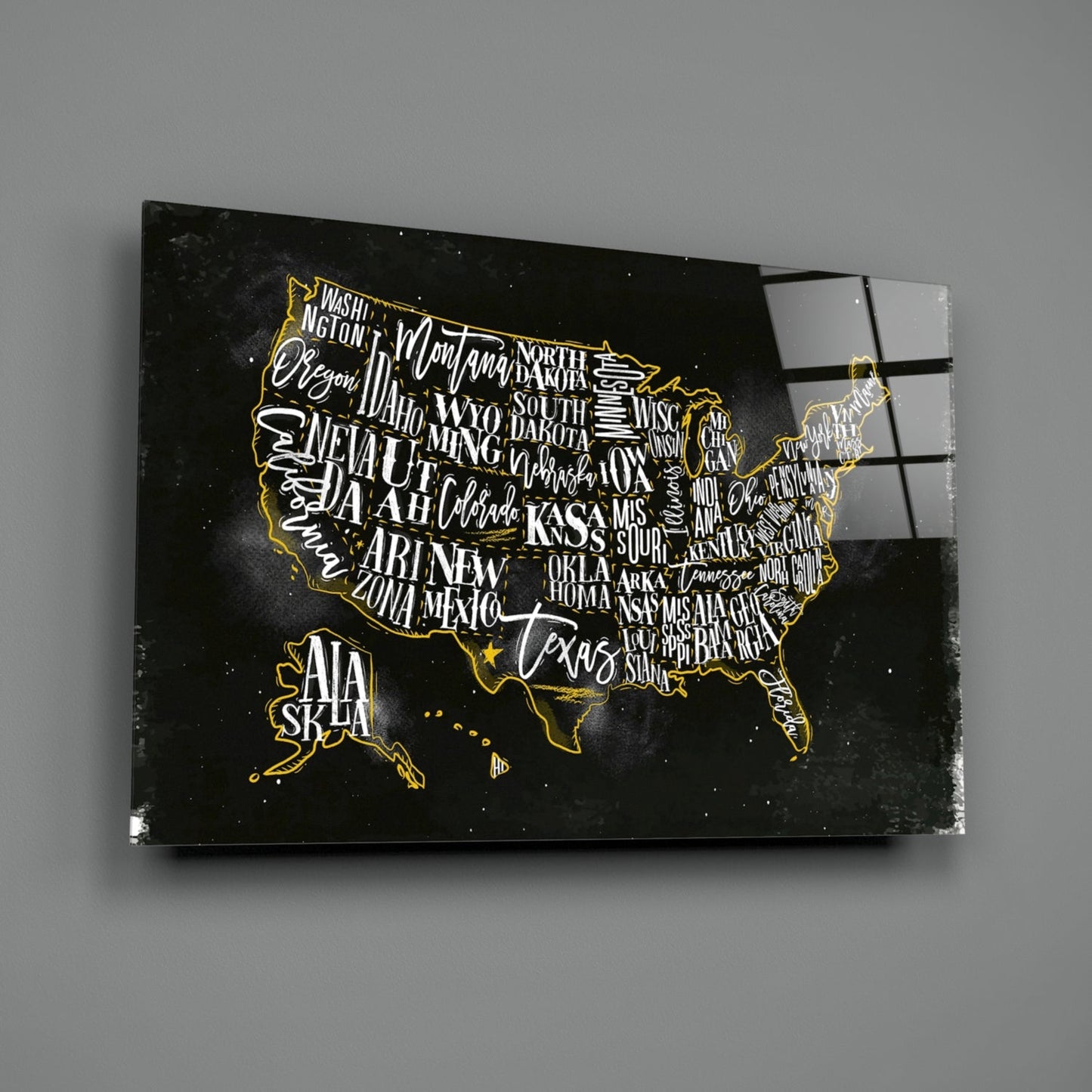 Black glass wall art featuring a gold-outlined USA map with white state names on dark background, angled view showing reflection.