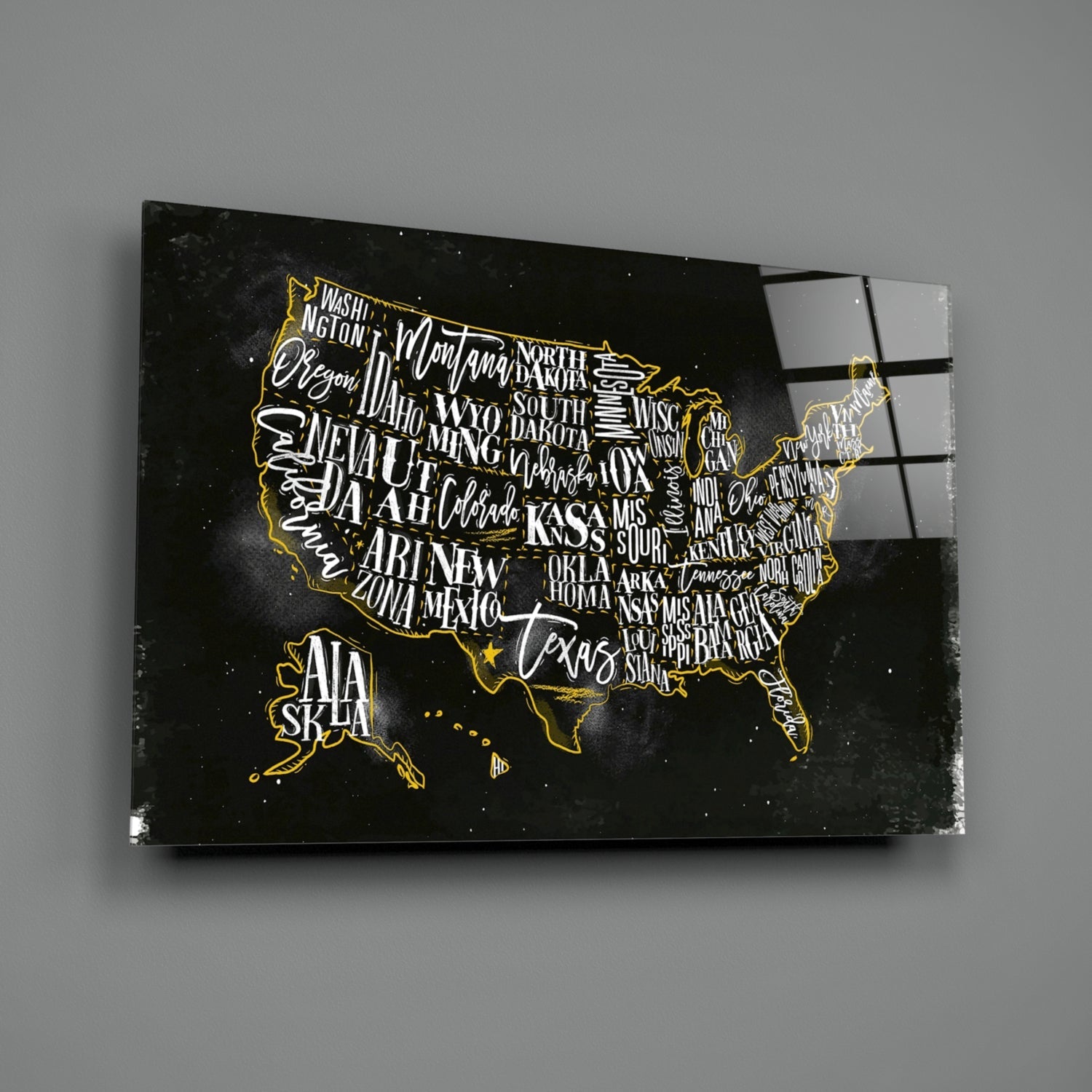 Black glass wall art featuring a gold-outlined USA map with white state names on dark background, angled view showing reflection.