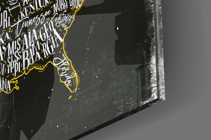 Close-up detail of glass wall art showing yellow-outlined USA map with white text on dark background, angled perspective view.