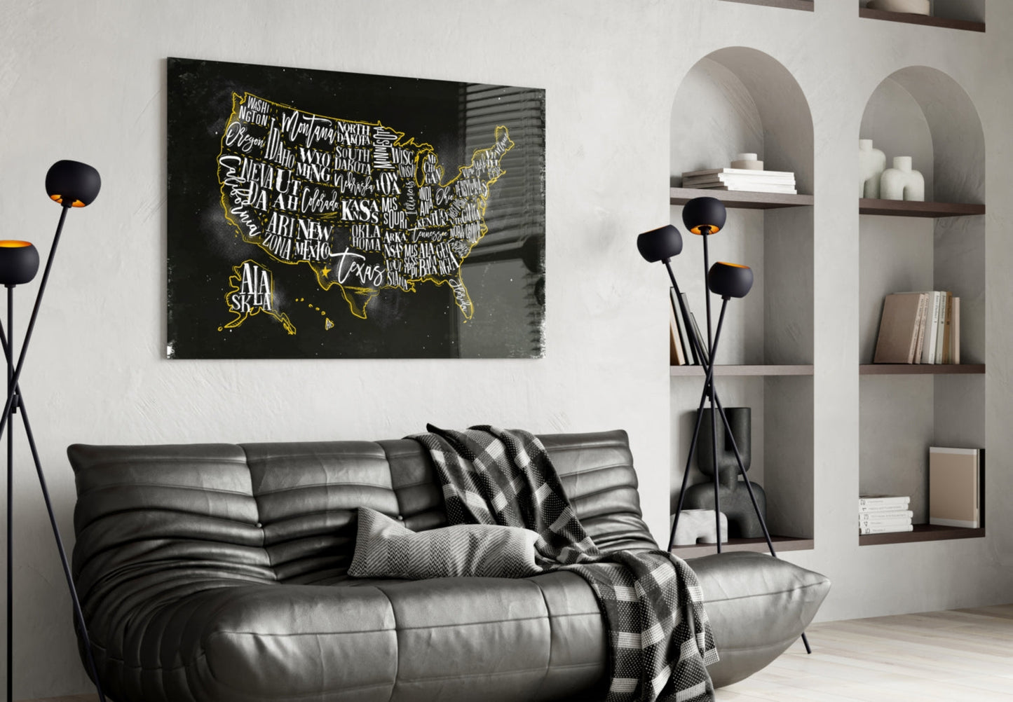 Black glass USA map with gold state outlines and white typography displayed above gray leather sofa in modern living room.