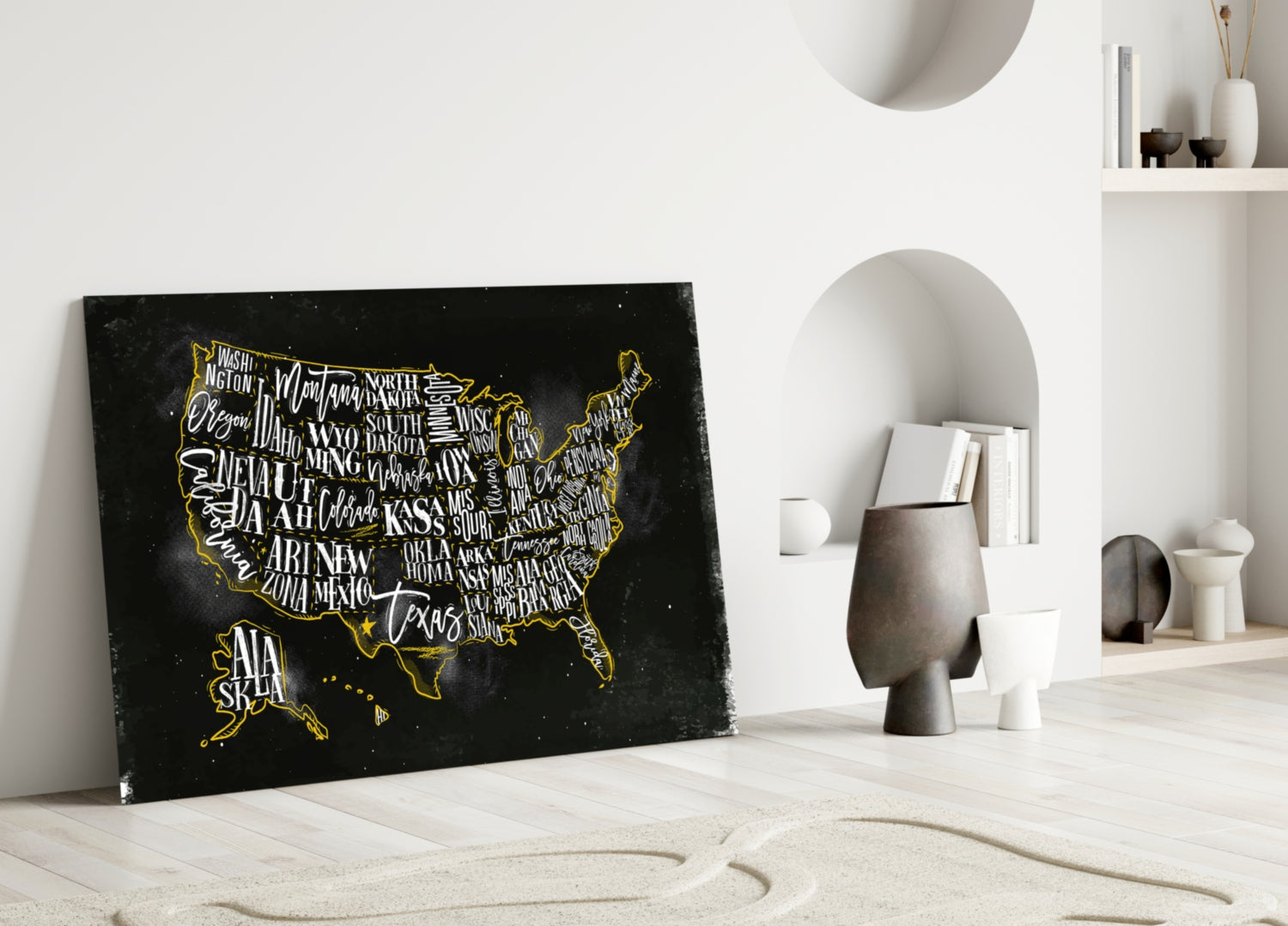 Black glass USA map with gold state names and border leaning against white wall beside decorative objects.