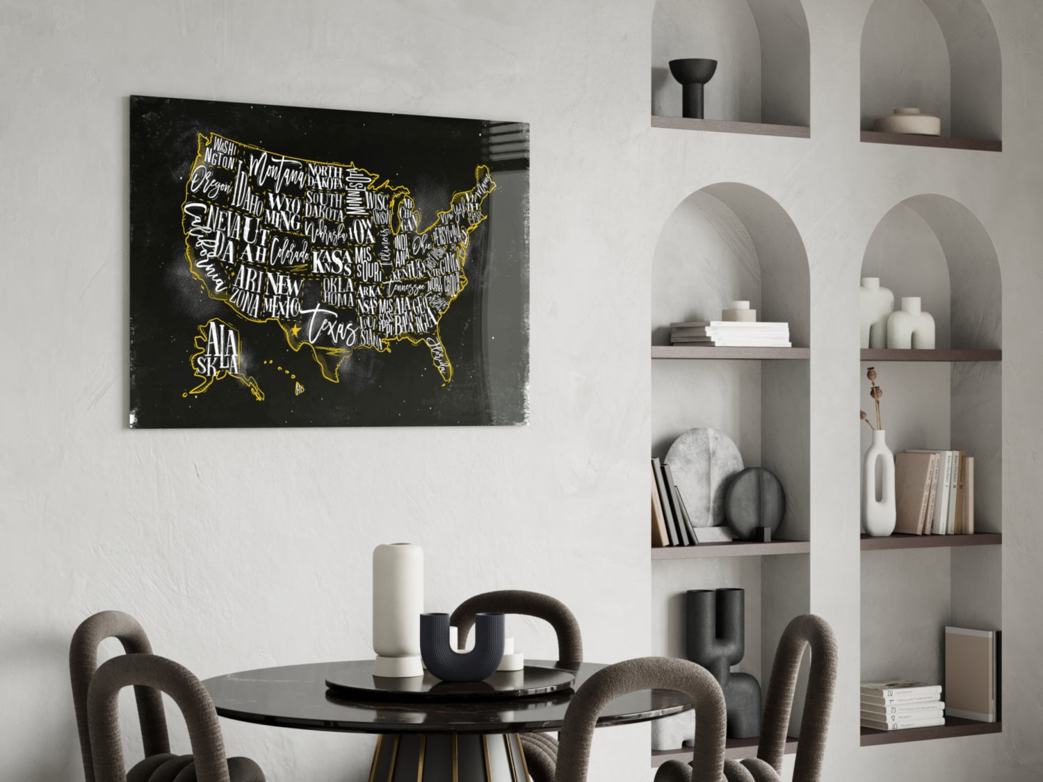Black glass USA map with gold state names and borders displayed above round dining table in modern interior with white built-in shelving.