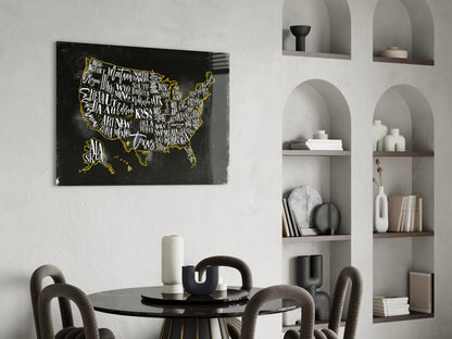 Black glass USA map with gold state names and borders displayed above round dining table in modern interior with white built-in shelving.