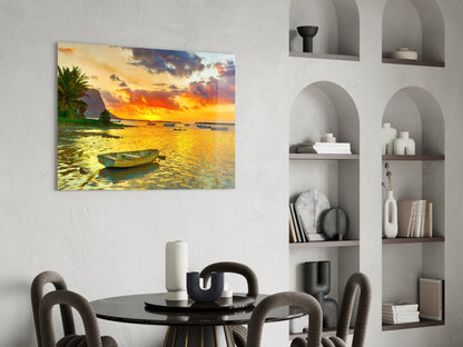 Tropical sunset seascape with moored fishing boats and palm trees reflected in golden water.