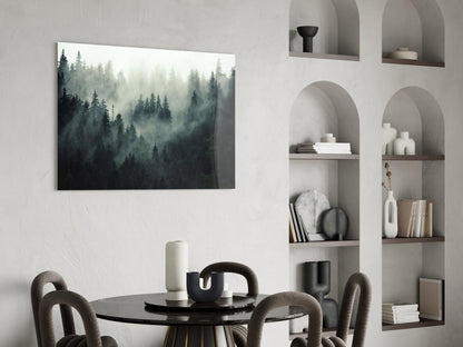 Misty forest landscape glass wall art displayed above black dining table with grey upholstered chairs.
