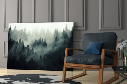 Misty forest glass wall art displayed in a modern living room beside a wooden chair with black cushioning and blue pillow.