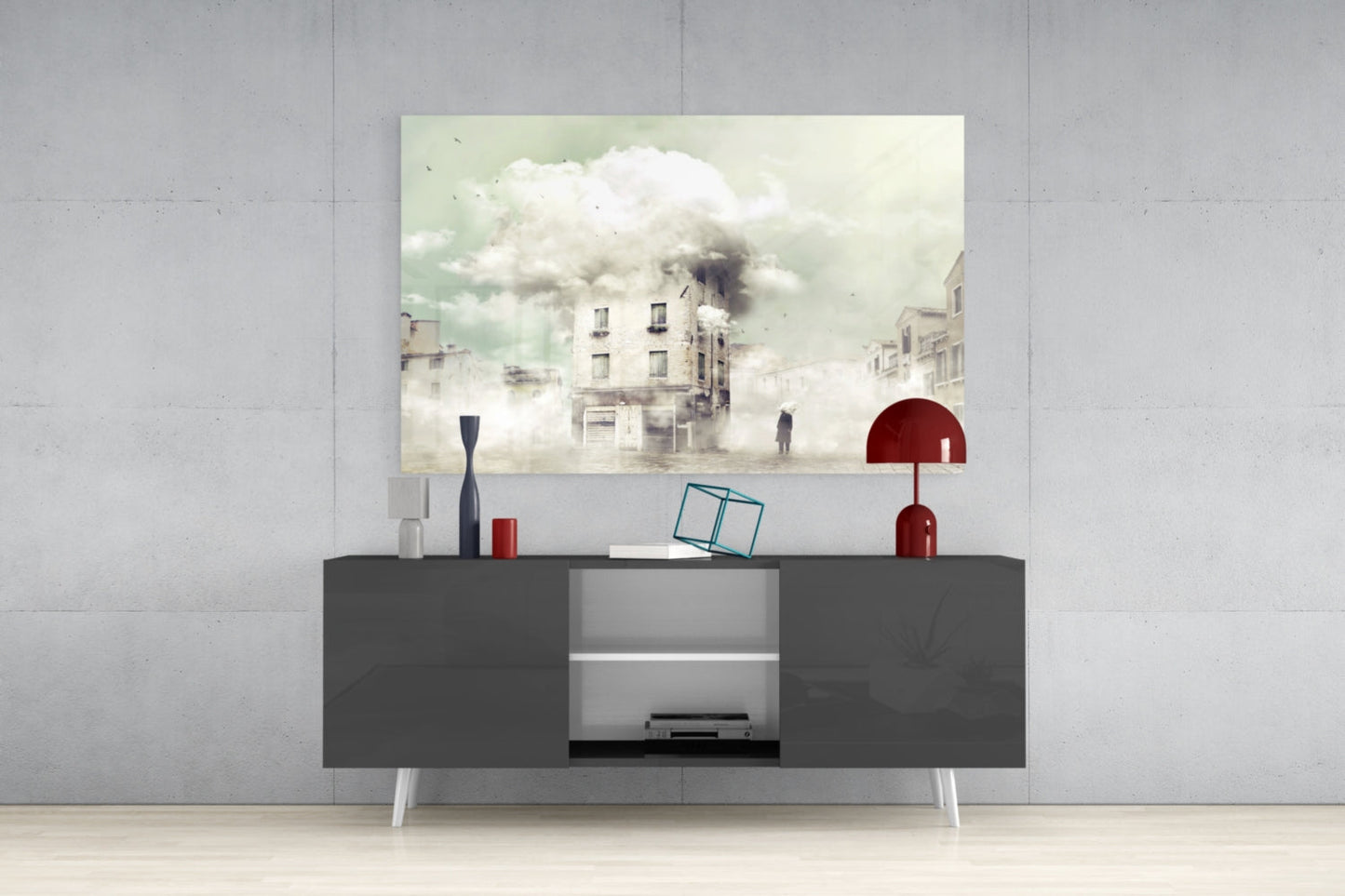 Modern living room styled with gray media console displaying surreal foggy cityscape glass wall art above, accented with red lamp and decorative objects.