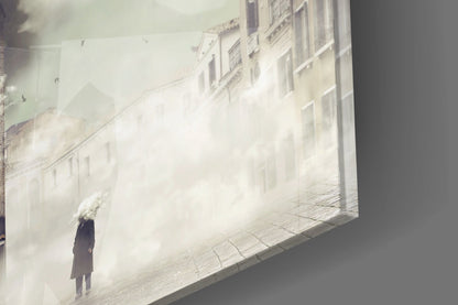 Fog Glass Wall Art mounted on gray wall displaying a solitary figure in dark coat standing in misty European street with pale buildings.