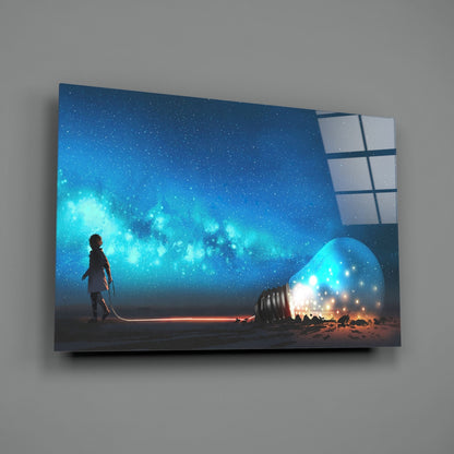 Glass wall art panel displaying a silhouetted figure standing beside a glowing light bulb under a starry blue sky, mounted on gray wall.