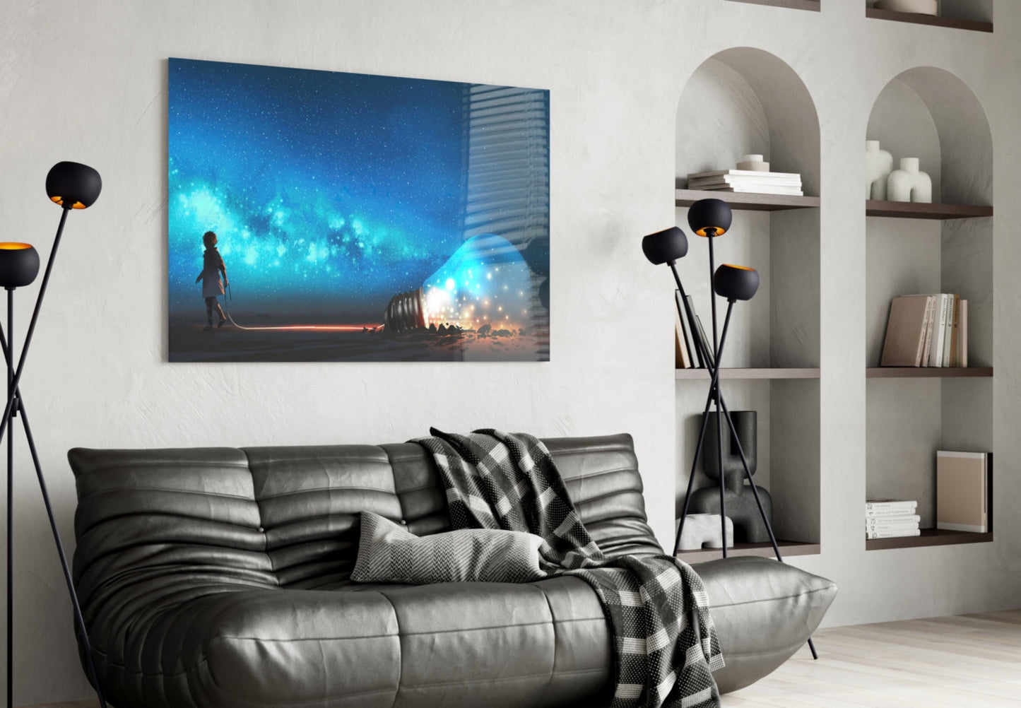 Glass wall art depicting a silhouetted figure holding a glowing lightbulb against a bright blue starry sky, displayed above a black leather sofa.