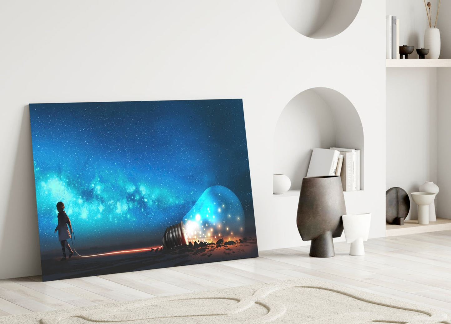 Glass wall art depicting a silhouetted figure holding a glowing blue orb beneath a starry night sky, leaning against a light wood floor beside white decorative objects.
