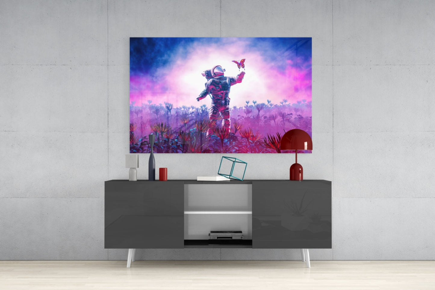 Glass wall art displaying a neon-lit astronaut in a vibrant purple and pink alien landscape with butterflies, mounted above a dark media console.