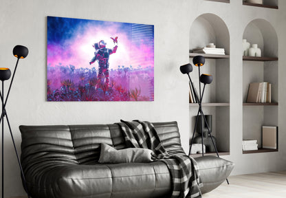 Glass wall art depicting an astronaut in a colorful pink and purple alien landscape with butterflies, displayed above a black leather sofa.
