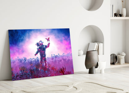 Colorful glass art panel leaning against white wall shows astronaut in spacesuit reaching toward butterfly above vibrant purple and pink alien landscape.