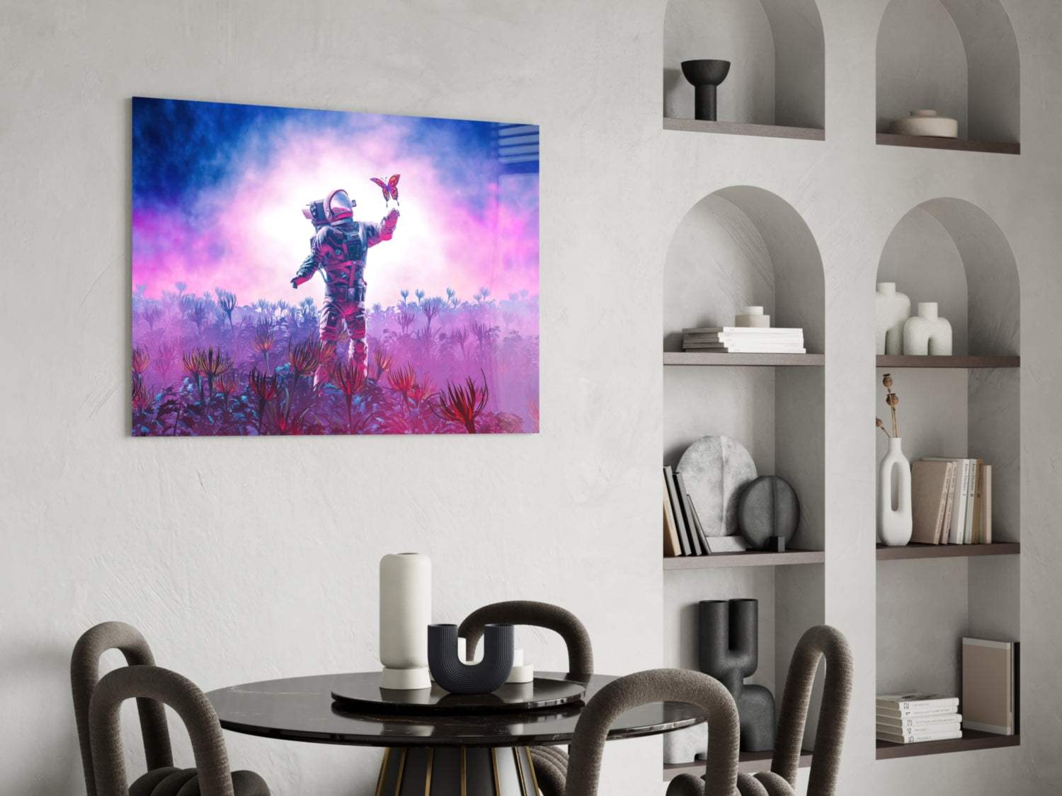 Vibrant glass wall art depicting an astronaut in a purple and pink alien landscape with butterflies, displayed above a round black dining table.