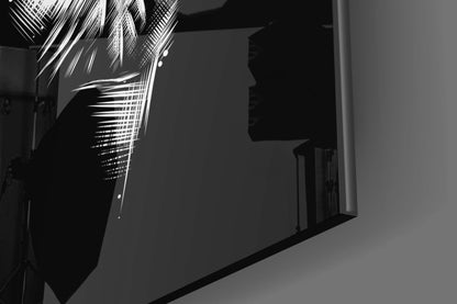 Black and white photograph of glass wall art featuring hands and horn shapes casting dramatic shadows on a gray wall.