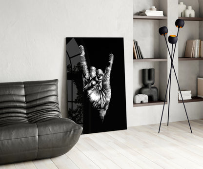 Black and white glass wall art depicting a hand making a peace sign, displayed in a modern living room with gray sofa and shelving.