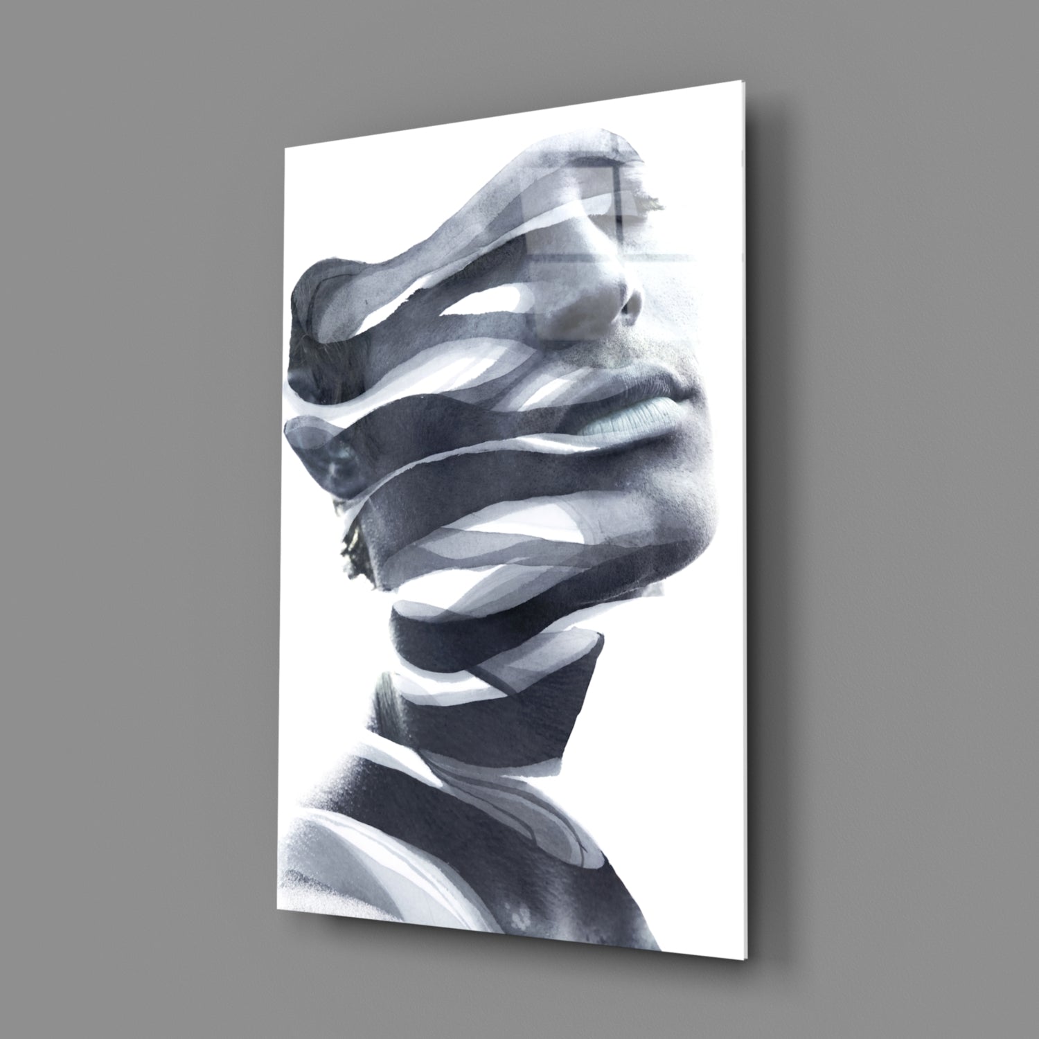 Black and white portrait of man's face wrapped in horizontal white ribbons, mounted on gray wall.
