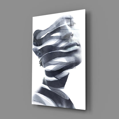 Black and white portrait of man's face wrapped in horizontal white ribbons, mounted on gray wall.