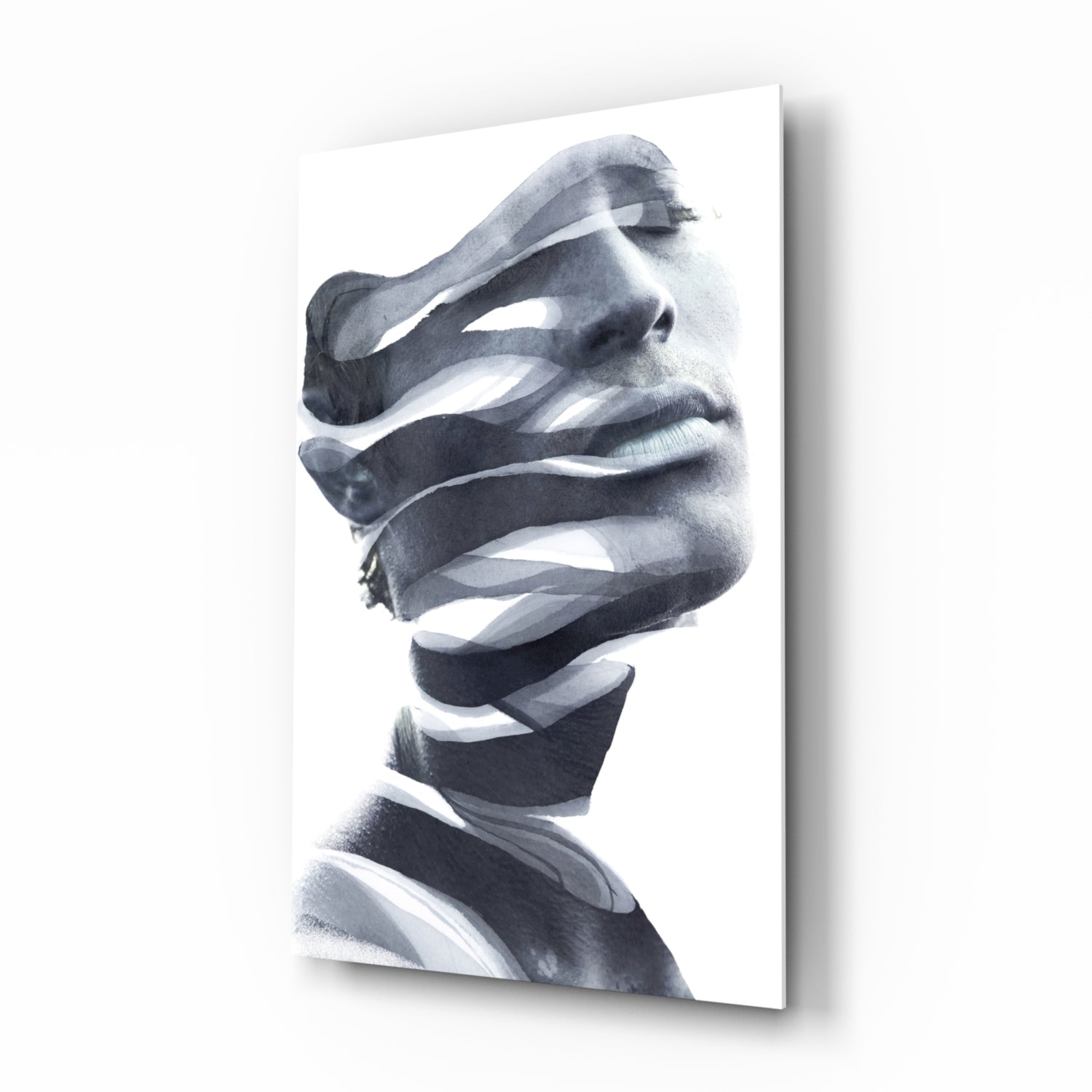 Monochrome glass wall art featuring a man's face in profile with abstract white ribbon-like strips obscuring his features, mounted at an angle.