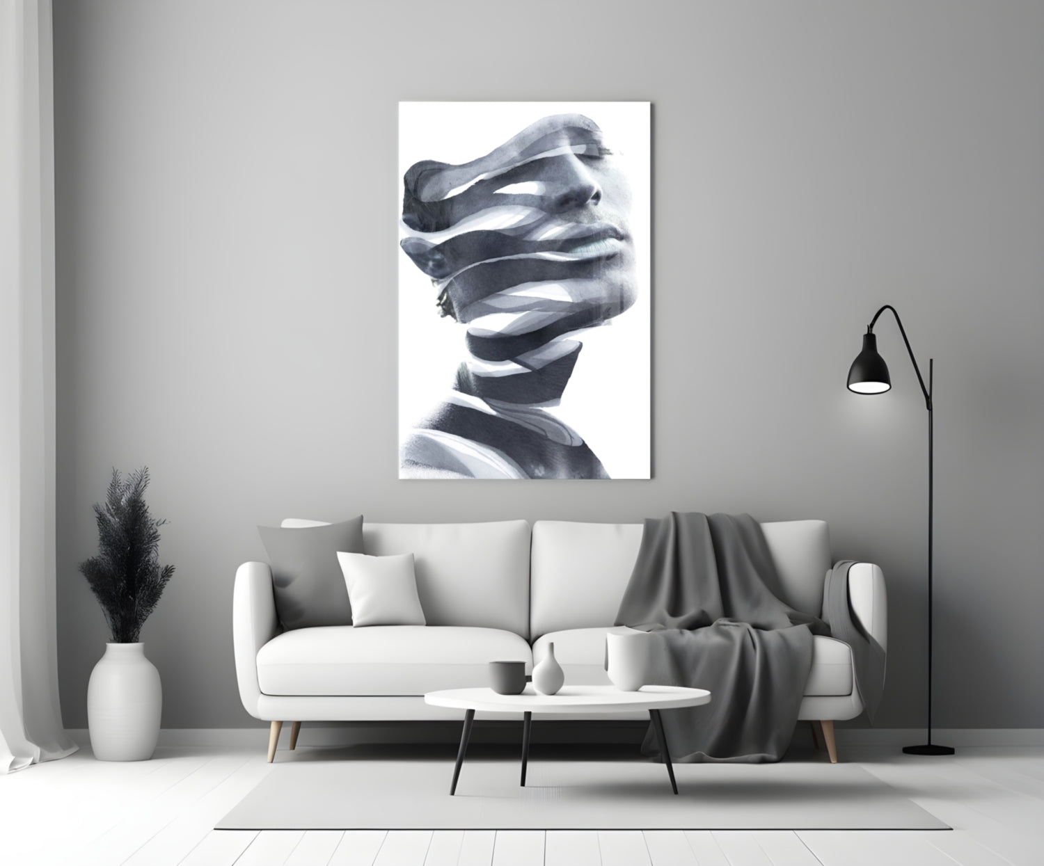 Black and white glass wall art depicting a stylized male head wrapped in translating ribbons, displayed above a gray sofa in a modern living room setting.