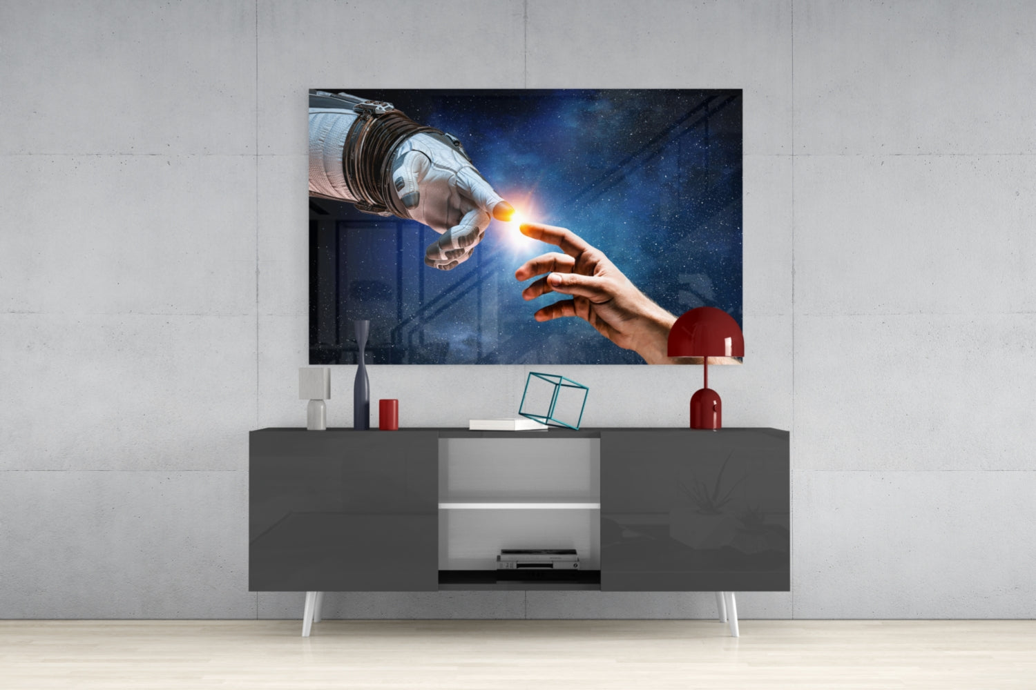 Modern living room setup featuring a glass wall art panel displaying an astronaut and human hand touching with a glowing light, mounted above a dark gray media console with white legs.