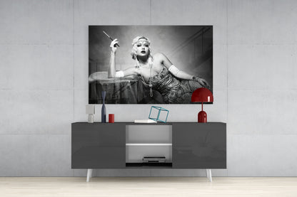 Black and white vintage-style glass wall art depicting a 1920s woman with cigarette holder displayed above gray media console with red accents.