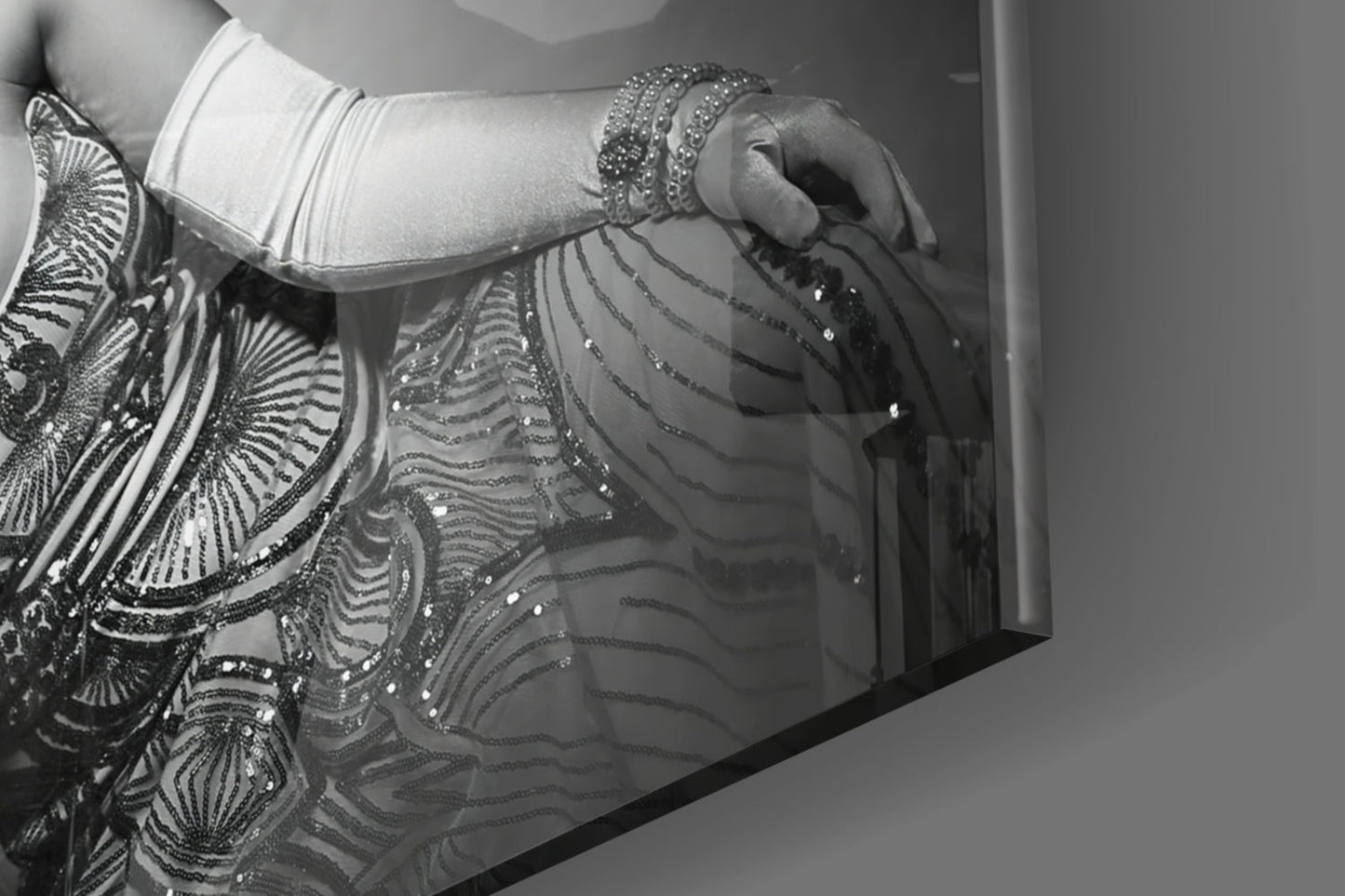Close-up detail of ornate black and silver beaded fringe against white fabric and gray wall surface.