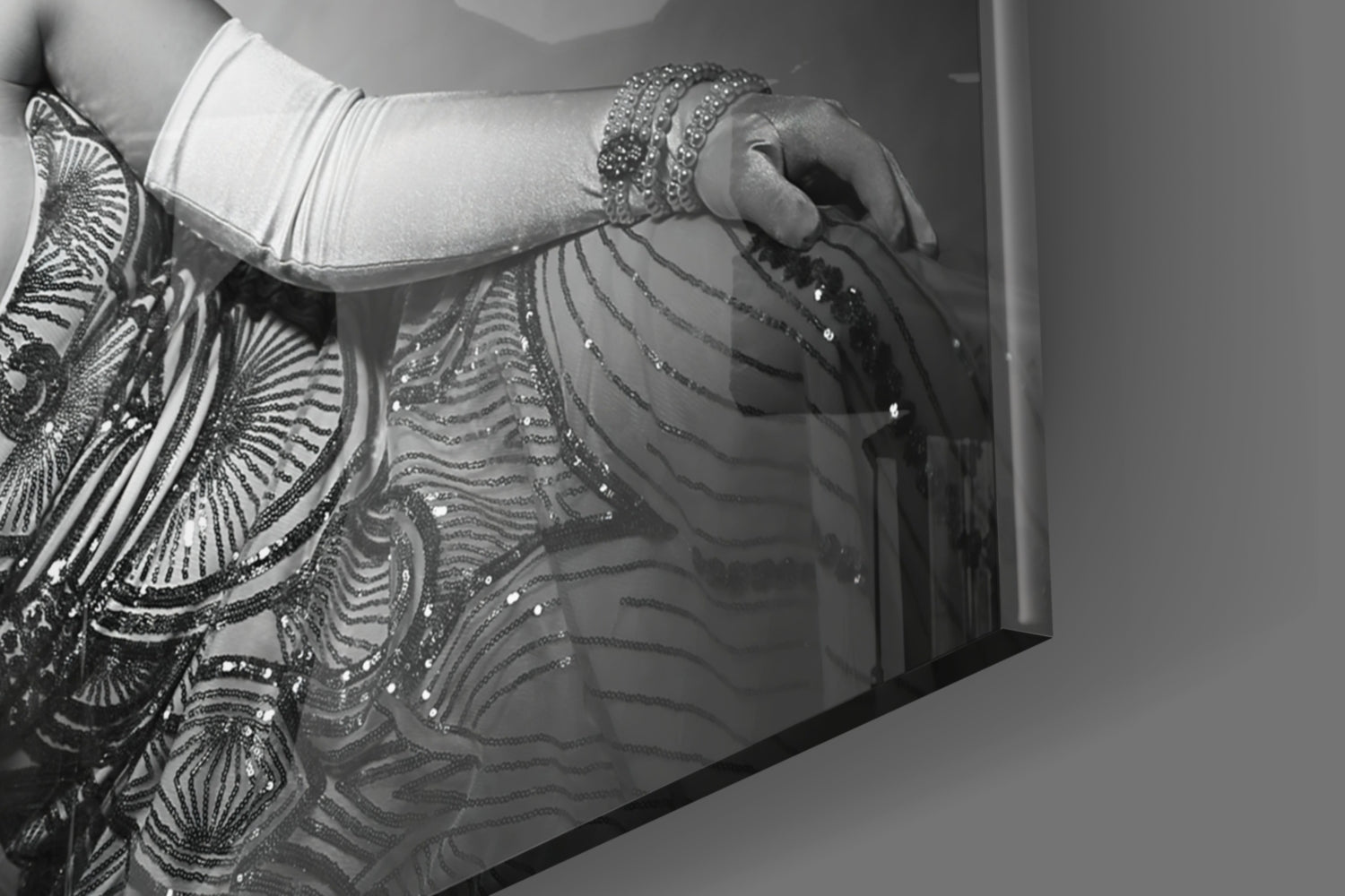 Close-up detail of ornate black and silver beaded fringe against white fabric and gray wall surface.