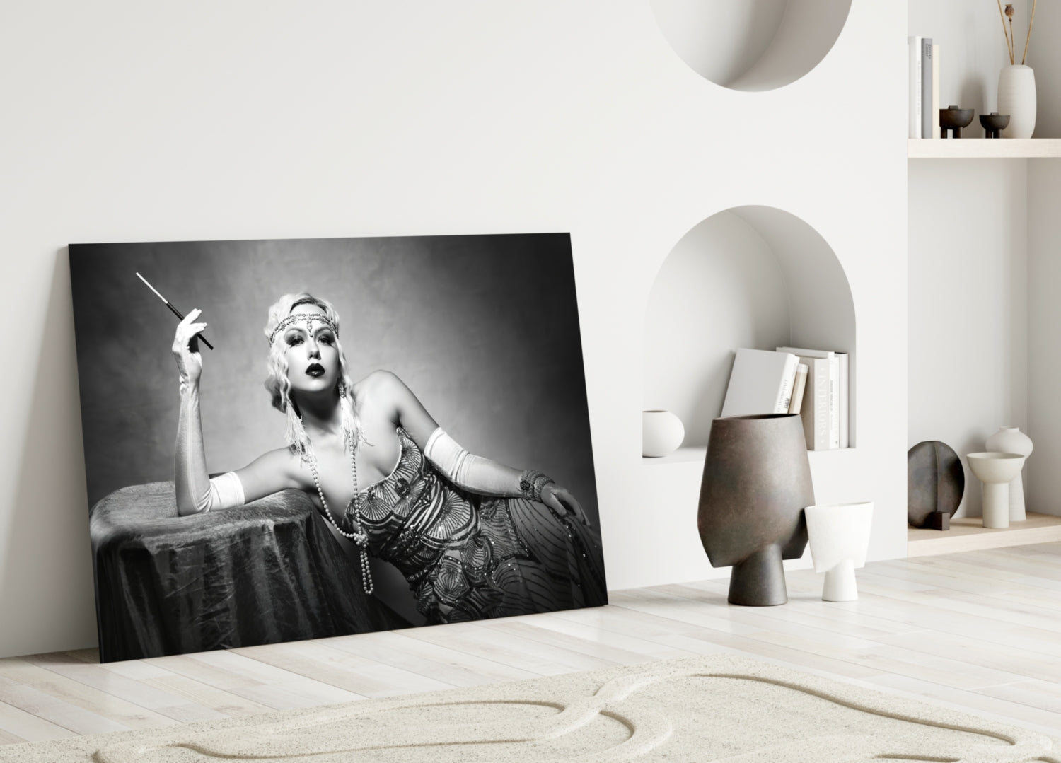 Black and white glass wall art depicting a 1920s-styled woman with cigarette holder and pearl necklace, leaning against beige interior decor.
