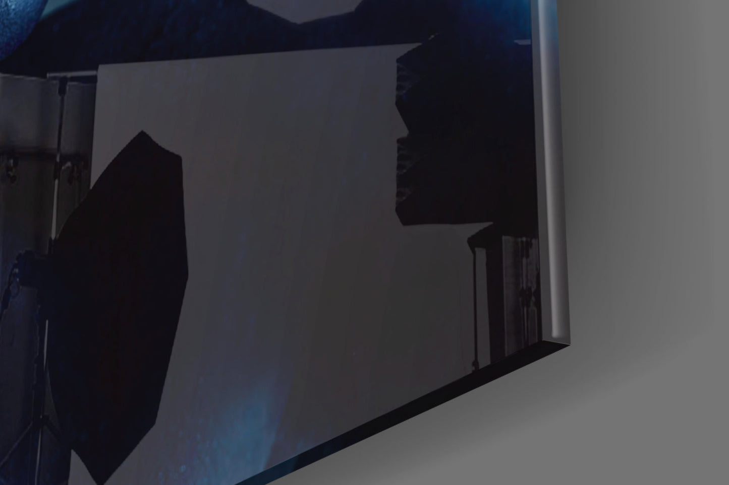 Silhouetted glass wall art panel mounted on white wall, showing dark abstract figures against translucent background, angled perspective view.