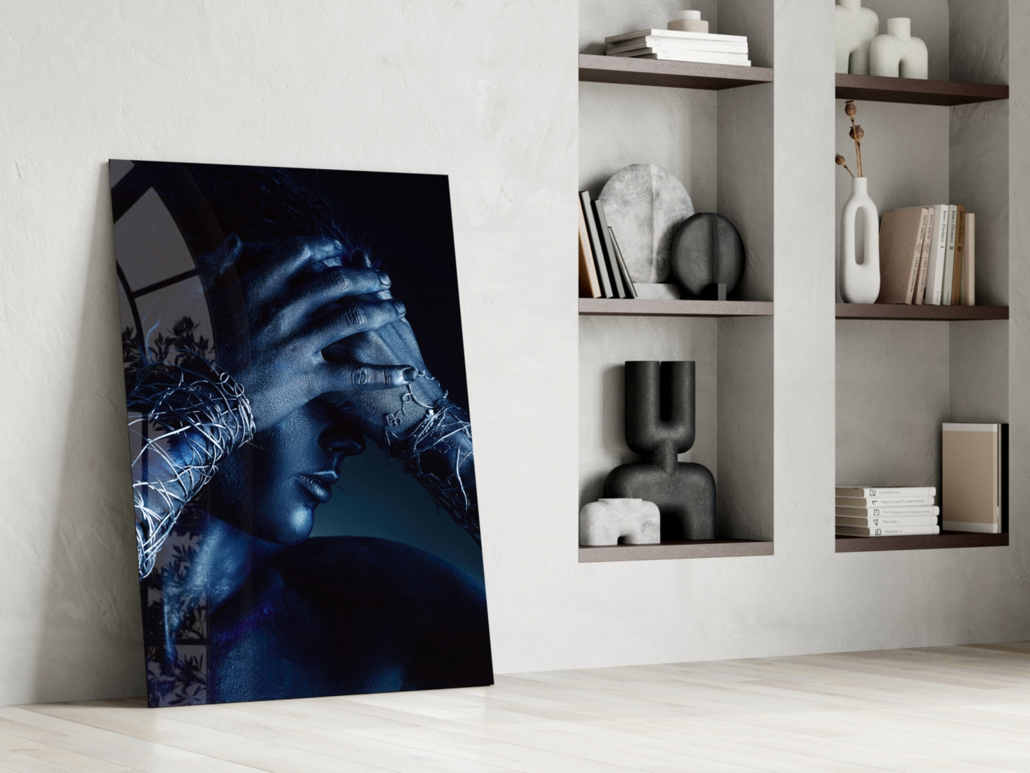 Deep Thought Glass Wall Art leaning against white wall beside built-in shelving displaying decorative objects and books.