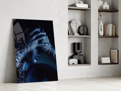 Deep Thought Glass Wall Art leaning against white wall beside built-in shelving displaying decorative objects and books.
