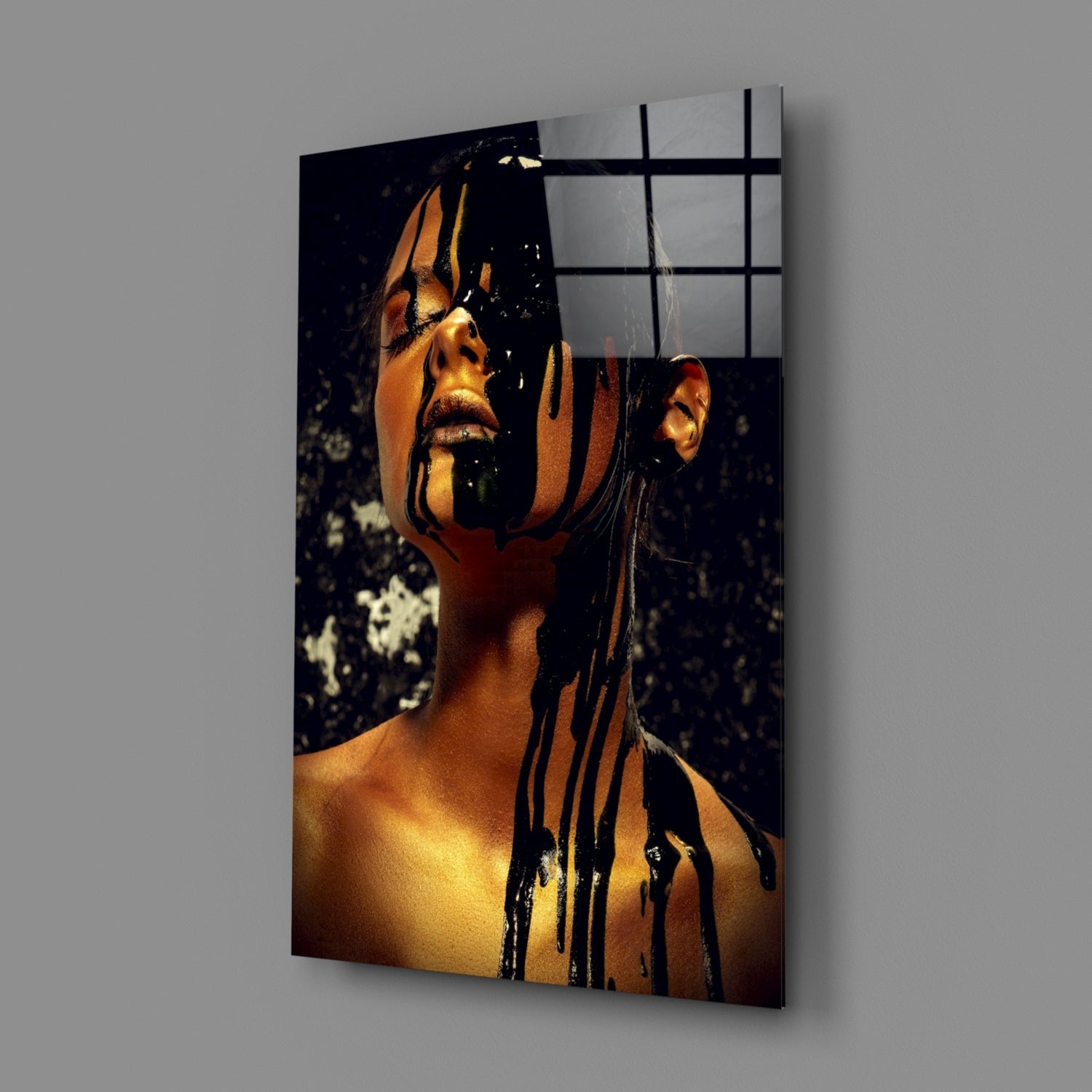 Angled view of stained glass wall art featuring a woman's portrait with gold-toned skin and black dripping paint effect against dark background.