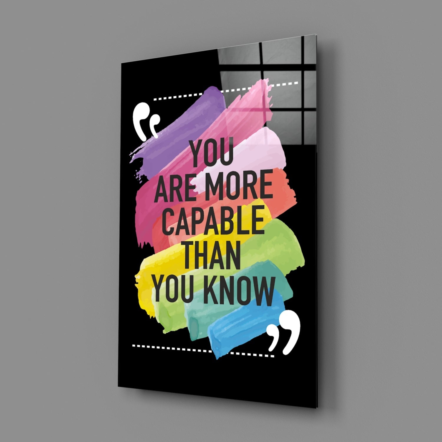 Angled 3/4 view of black glass wall art with colorful watercolor brushstrokes and motivational text in multiple colors.