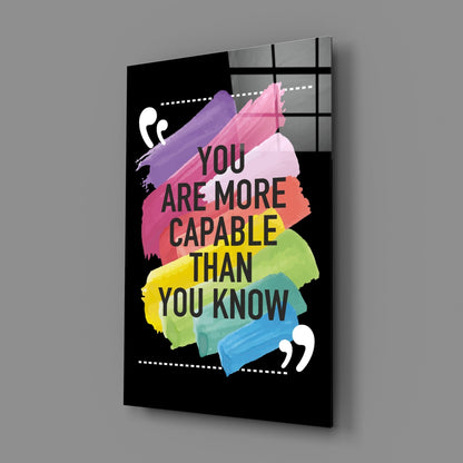 Angled 3/4 view of black glass wall art with colorful watercolor brushstrokes and motivational text in multiple colors.