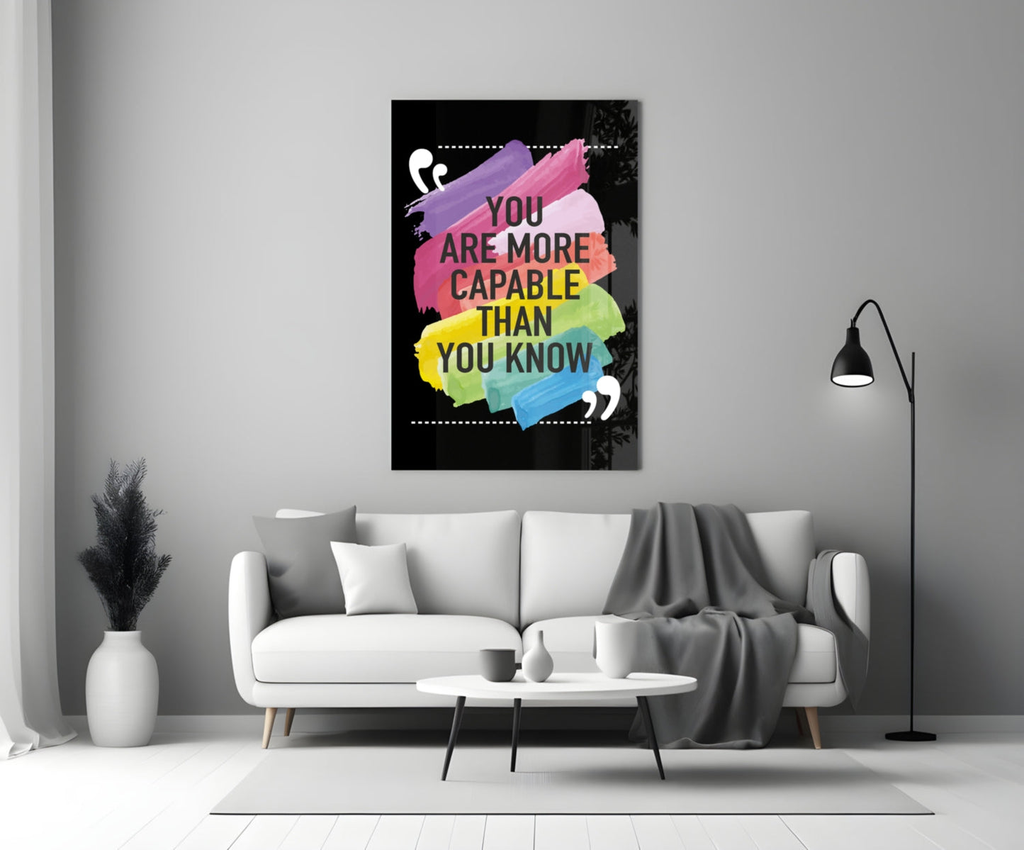 Motivational glass wall art with colorful watercolor brushstrokes and black text mounted above white sofa in modern living room.
