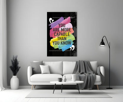 Motivational glass wall art with colorful watercolor brushstrokes and black text mounted above white sofa in modern living room.