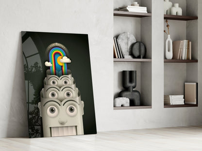 Surreal glass art leaning against white wall shows cream-colored head with multiple eyes topped by colorful rainbow and clouds on dark background.