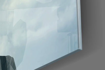 Frosted glass wall art panel mounted indoors showing translucent silhouettes of balloon-headed figures against soft blue-white tones.